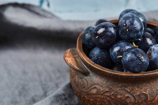 Ripe plums in a bowl on gray tablecloth