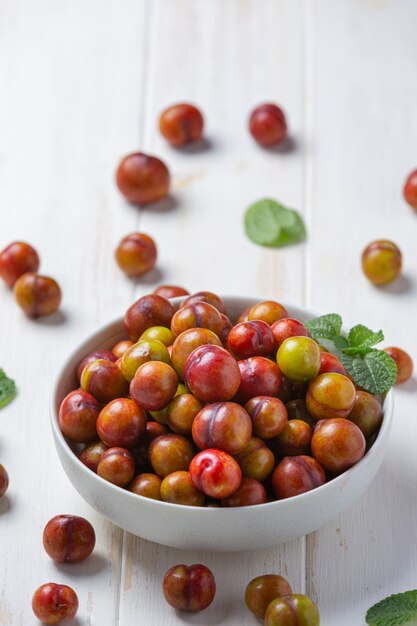 Ripe plums on the white wooden surface.