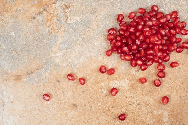 Ripe pomegranate seeds on marble surface.