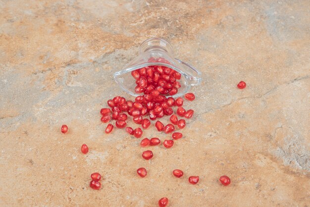 Ripe pomegranate seeds on marble surface.