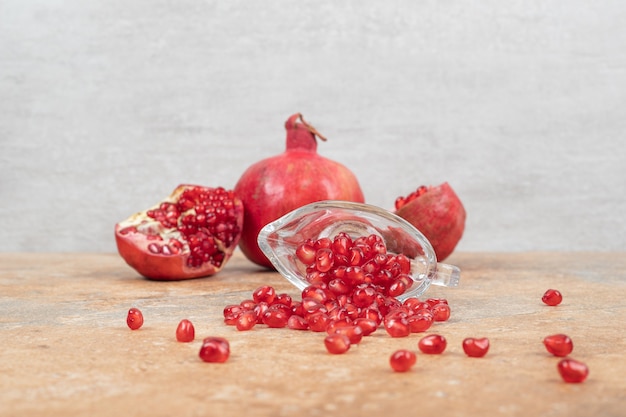 Ripe pomegranates and seeds on marble surface.