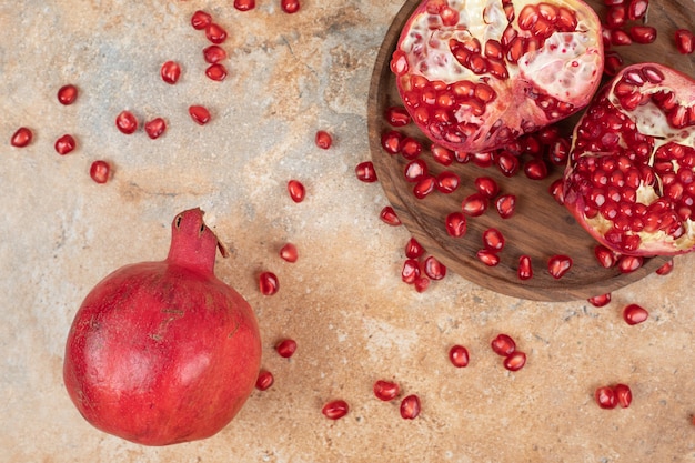 Free photo ripe pomegranates and seeds on marble surface.