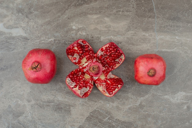 Ripe pomegranates and seeds on marble table.