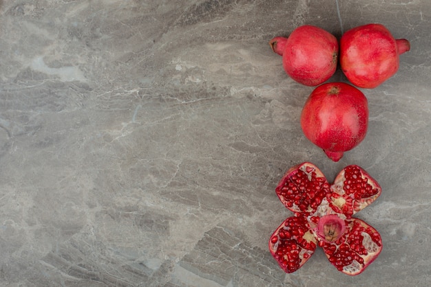 Ripe pomegranates and seeds on marble.