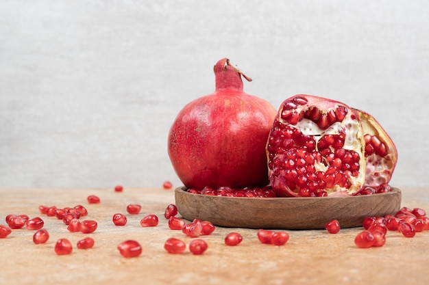 Ripe pomegranates and seeds on wooden plate. 