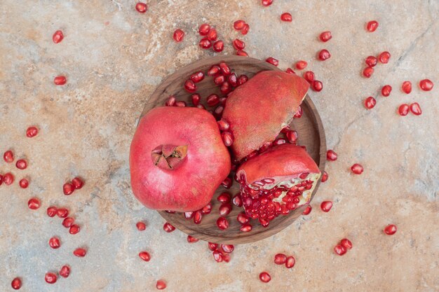 Ripe pomegranates and seeds on wooden plate. 