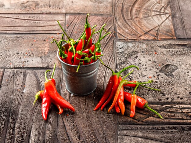 Ripe red peppers in a mini bucket high angle view on a stone tile background