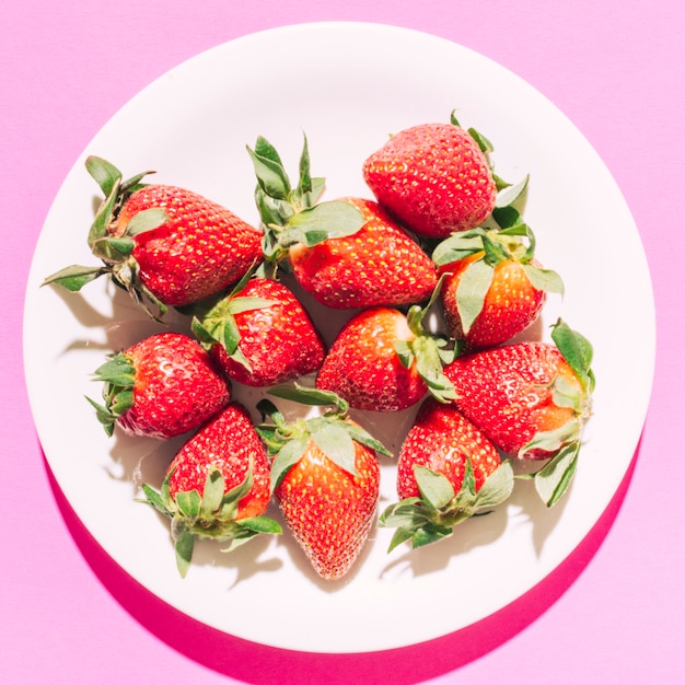 Ripe red strawberry with green stem on plate