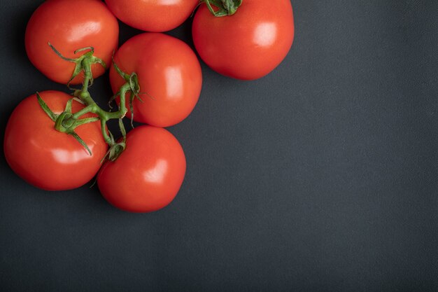 Ripe red tomatoes on dark surface