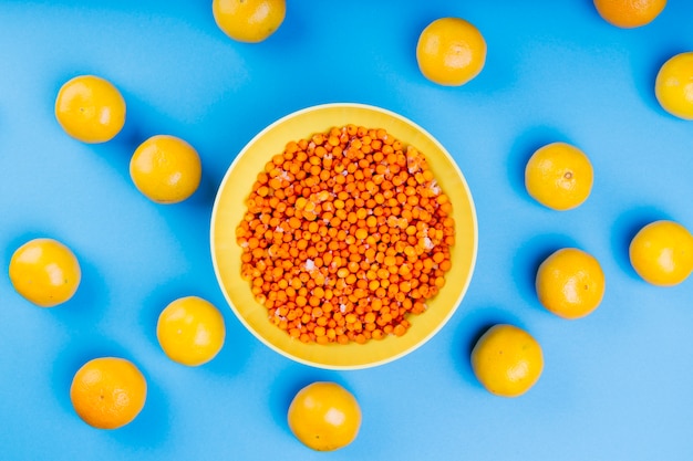 Спелые ягоды облепихи в желтой тарелке в окружении желтых лимонов