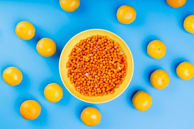 Ripe sea-buckthorn berries in yellow plate surrounded with yellow lemons