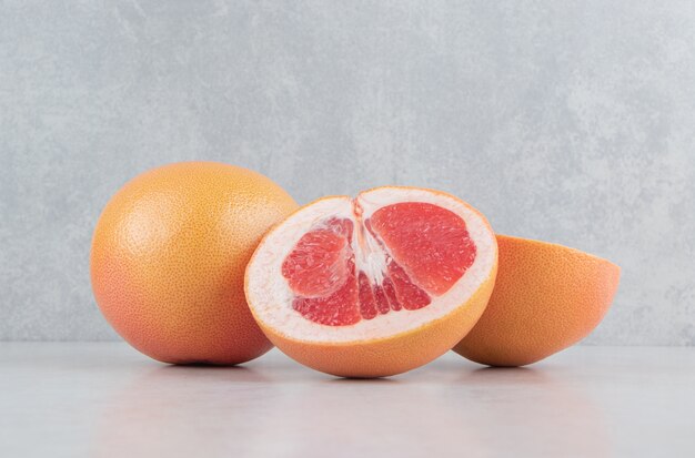 Ripe sliced grapefruits on stone table.