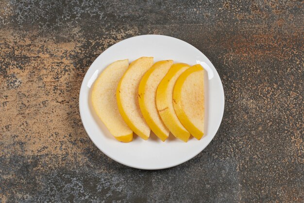 Ripe sliced quince on white plate. 