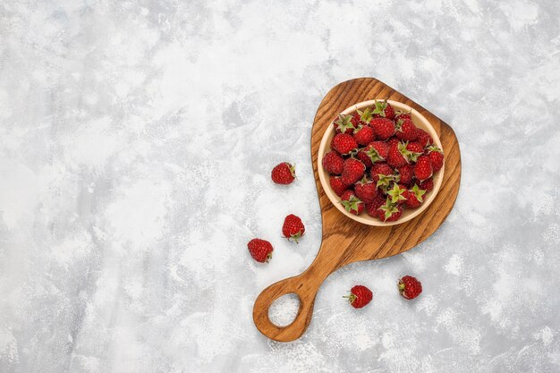 Ripe sweet raspberries in ceramic plate  on grey concrete . Close up, top view