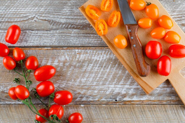 Ripe tomatoes with knife flat lay on wooden and cutting board