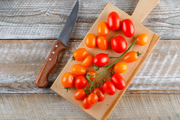 Ripe tomatoes with knife flat lay on wooden and cutting board