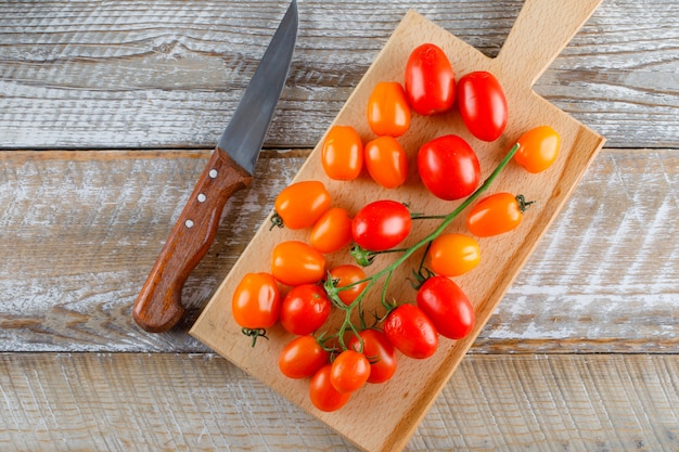 Ripe tomatoes with knife flat lay on wooden and cutting board