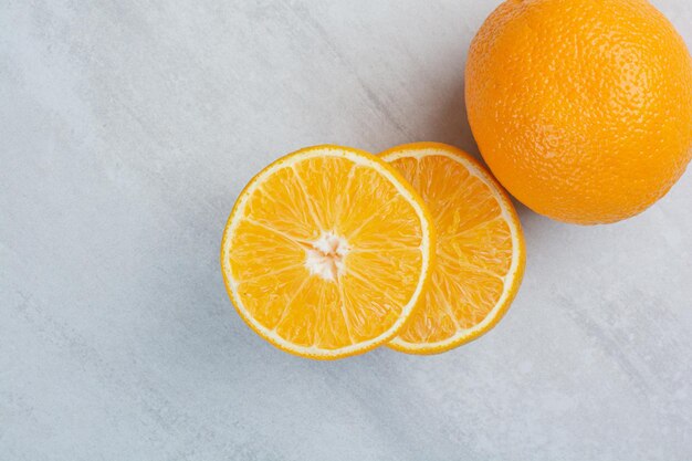 Ripe whole and half cut oranges on stone background. High quality photo