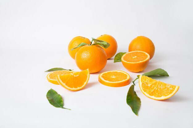 Ripe whole oranges with green leaves and sliced parts
