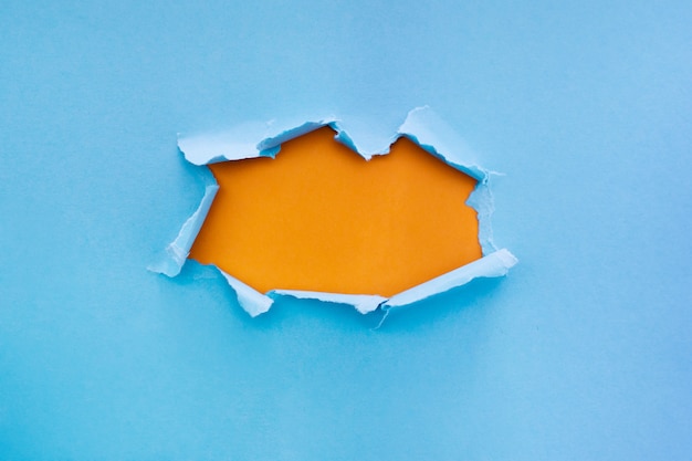 Ripped blue paper with orange color background with space for text