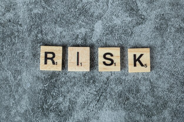 Risk writing with black letters on wooden dices on the marble background