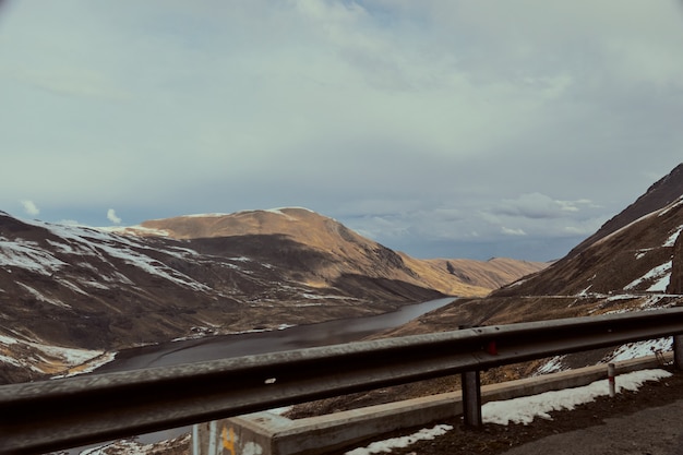 Free photo river flowing surrounded by the high mountains covered in snow in winter