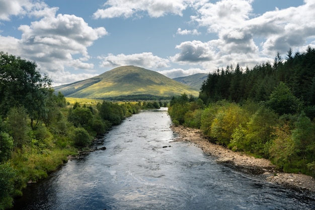 River Flowing Through The Trees And Mountains In Scotland