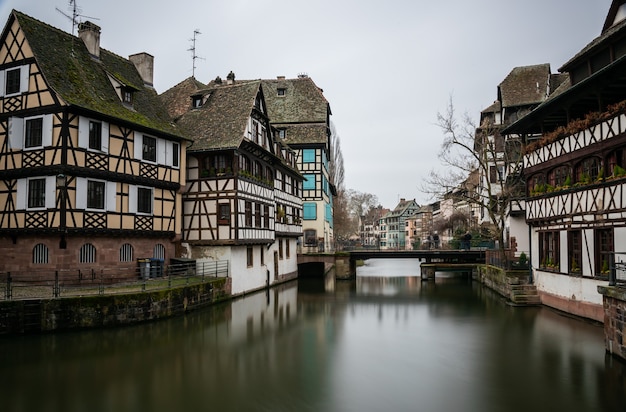 フランスのストラスブールの曇り空の下でプチフランスの建物に囲まれた川