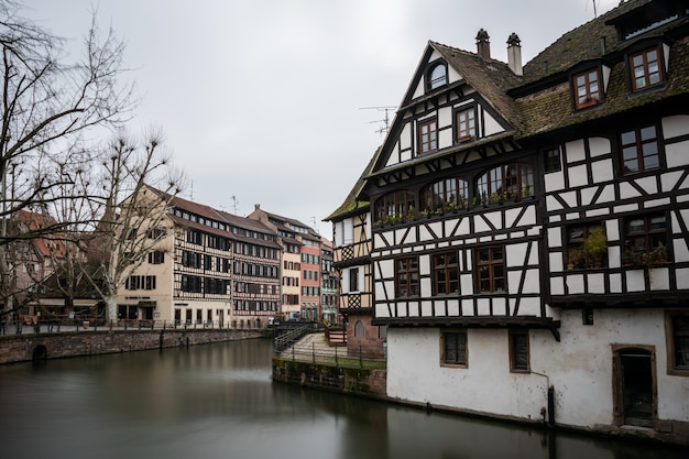 River surrounded by colorful buildings and greenery under a cloudy sky in Strasbourg in France