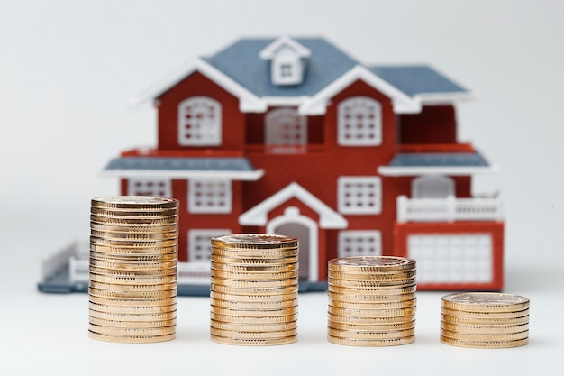 Le monete rmb impilate davanti al modello di abitazione (prezzi delle case, acquisto di immobili, immobiliare, concetto di mutuo)