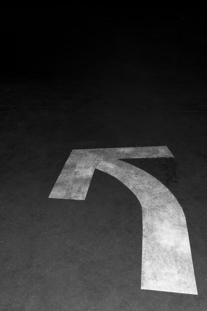 Road arrow sign in the night on asphalt