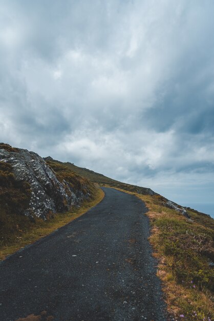 road on the hill with nobody walking under the cloudy sky