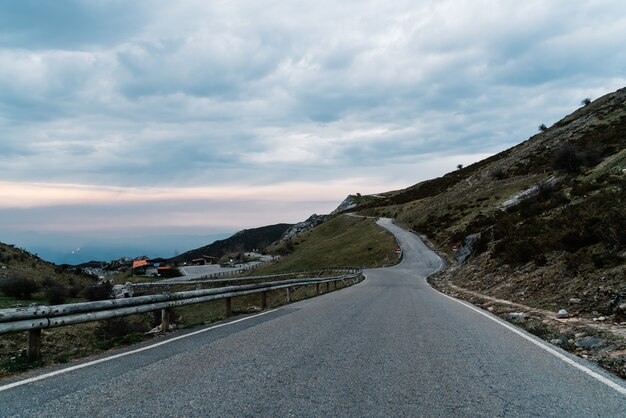 저녁에 흐린 하늘 아래 산으로 둘러싸인 도로