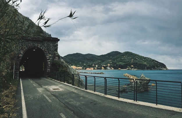 Free photo road towards a tunnel in the mountain near a sea with mountains