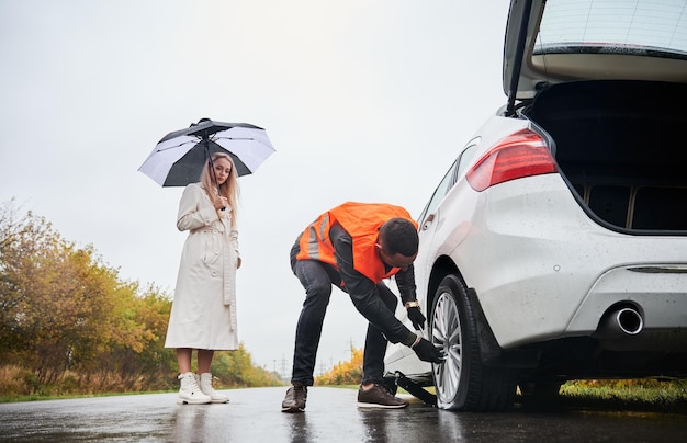 Roadside assistance worker repairing woman vehicle on the street