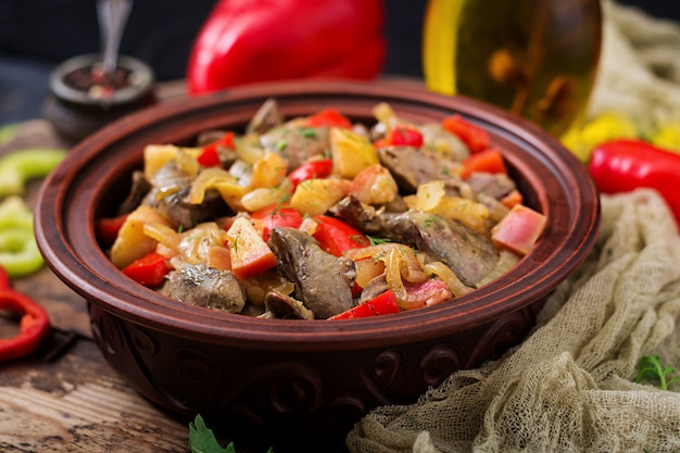 Roast chicken liver with vegetables on wooden background.