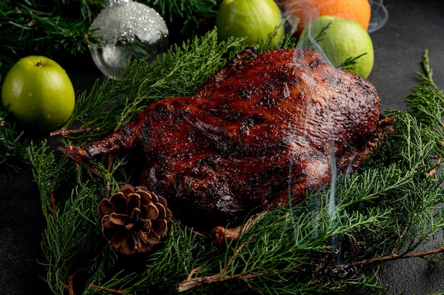 鴨​の​ロースト​は​、​緑​の​枝​が​あり​、​松ぼっくり​で​飾られた​プレート​で​提供されます​。​暗い​クリスマス​の​背景​に​皿