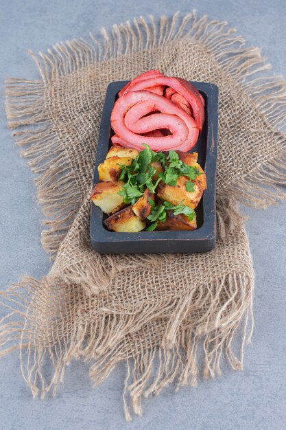 Roasted bacon and fried potato on black wooden plate. 