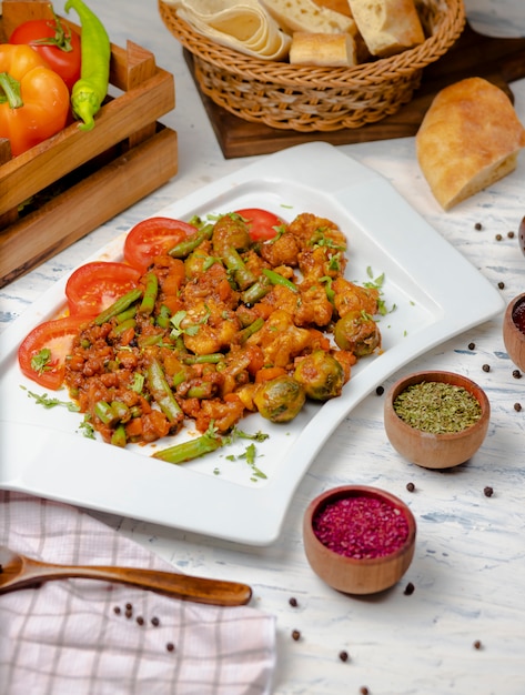 Foto gratuita cavolfiore arrosto con germogli, fagioli e servito con salsa di pomodoro ed erbe aromatiche