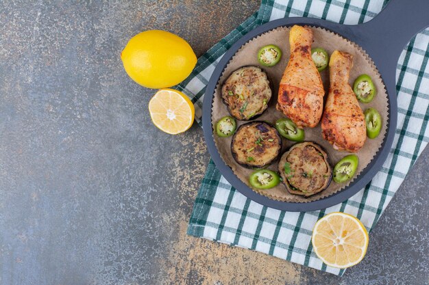 ダークボードに揚げ野菜とレモンを添えたローストチキンの脚。高品質の写真