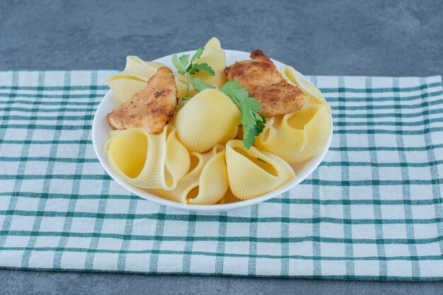 Roasted chicken nuggets and boiled pasta in white bowl. 