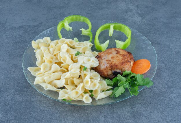 Roasted chicken and tasty pasta on glass plate.