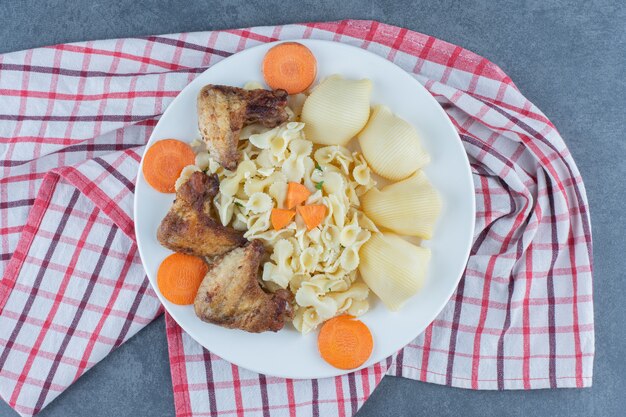 하얀 접시에 구운 닭 날개와 파스타.