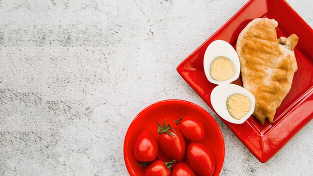 거친 배경에 삶은 계란과 토마토와 구운 닭 날개