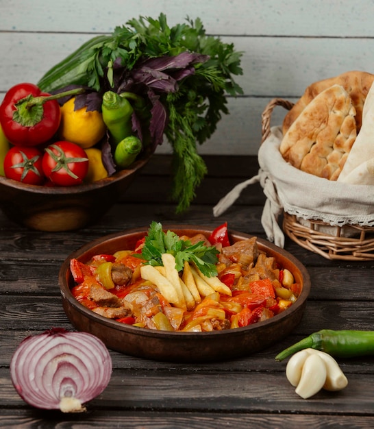 Roasted chicken with bell peppers, onion and tomato in pottery pan