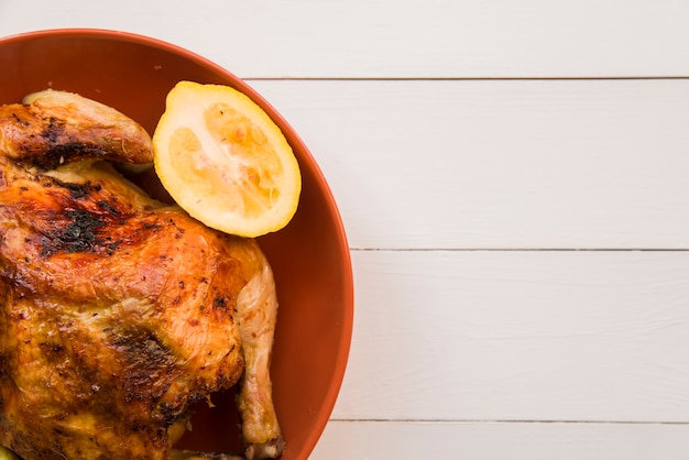 Roasted chicken with lemon on orange plate