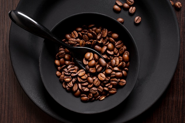 Жареные кофейные зерна в миске с ложкой
