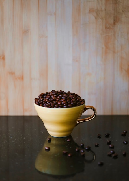 反射机の上に茶色のセラミックカップで焙煎コーヒー豆