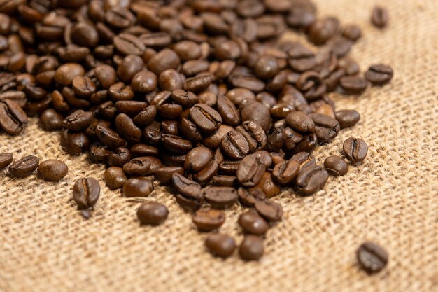 Roasted coffee beans isolated on burlap fabric background with free space for text