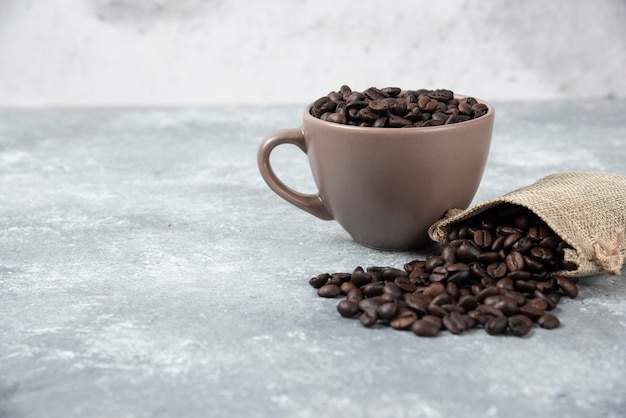 黄麻布の袋から大理石のカップに入れて焙煎したコーヒー豆。